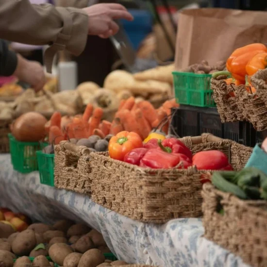 Produttori agricoli vendono frutta e verdura fresca in un mercato contadino frequentato dai consumatori